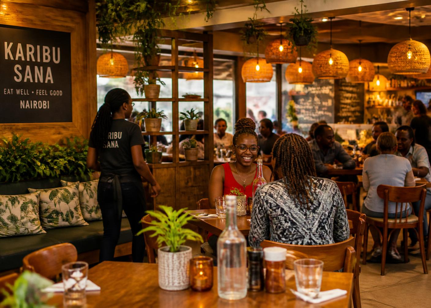 Warm, busy dining room at Greenview Restaurant with wooden tables, plants and amber pendant lights